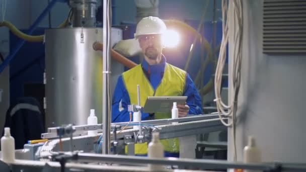 Técnico masculino está observando garrafas de plástico se movendo ao longo da correia — Vídeo de Stock