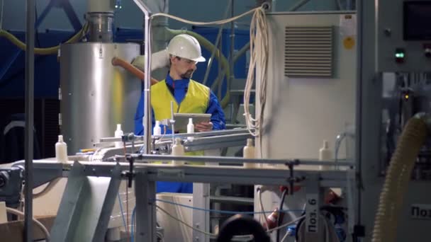 Ingeniero masculino está inspeccionando botellas de plástico en movimiento — Vídeo de stock