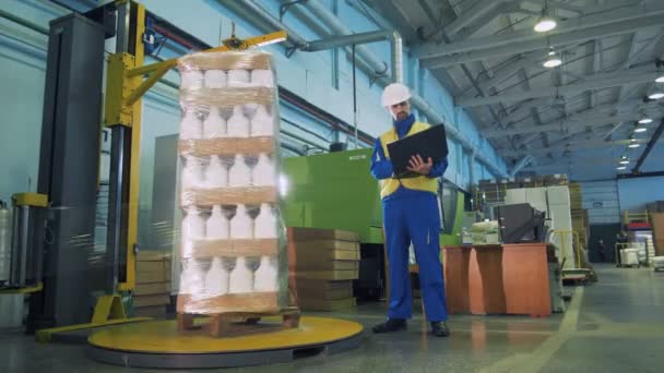 Polyethylen umwickelt Plastikkanister und ein männlicher Arbeiter beobachtet es — Stockvideo