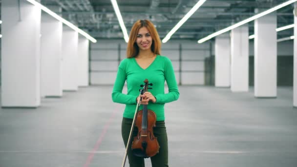 Chica sostiene un violín en las manos y sonríe a una cámara . — Vídeo de stock