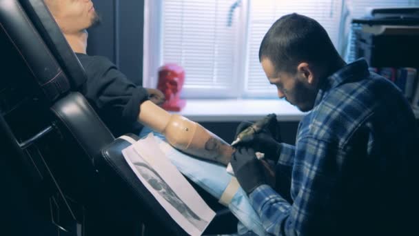 Tattoo master puttend uit een schedel een bionic hand, robot prothese. — Stockvideo