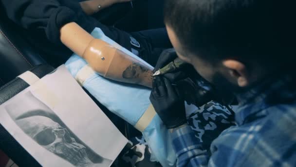Tatuaje moderno trabaja con el cliente discapacitado, dibujando en la mano protésica . — Vídeos de Stock