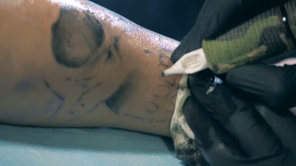 Een tattooes van de kunstenaar op een bionic prothese, handicap client. — Stockvideo