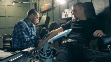 Engelli adam protez kolunu bir salonda dövme alır.