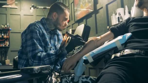 Professionell konstnär tatuera en person med konstgjorda arm. — Stockvideo