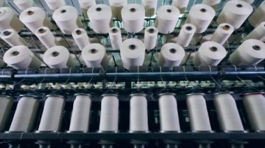 Dikiş ipliği mekanik bobin arasında hareket ediyor. Hazır giyim fabrika üretim ekipmanları.