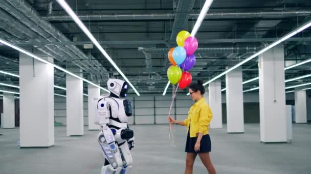 Amplio salón con un cyborg recibiendo globos de una chica — Vídeos de Stock