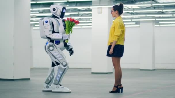 Robô alto está dando flores para uma mulher em um salão vazio — Vídeo de Stock