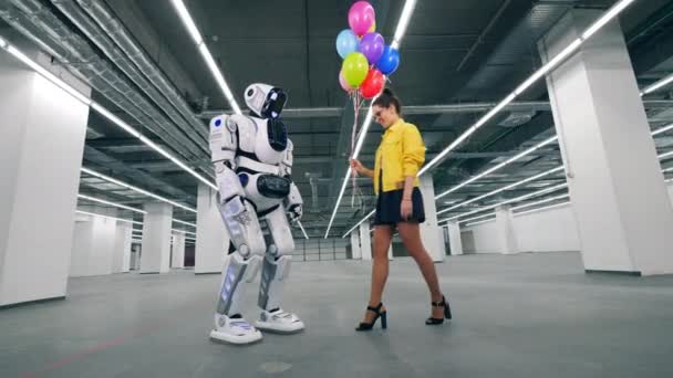 Человекоподобный робот и девушка держат шарики вместе. — стоковое видео