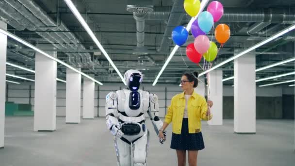 Дівчина з повітряними кулями йде з високим роботом — стокове відео