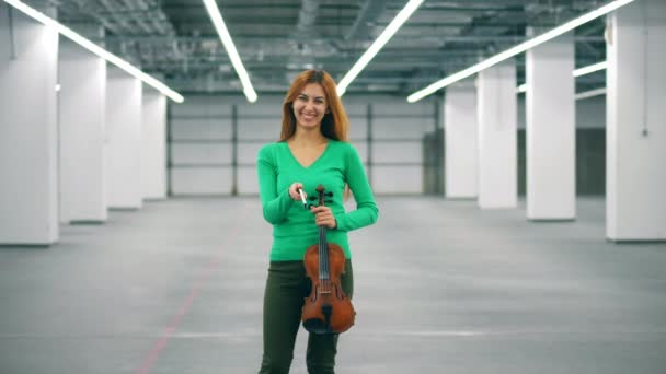 Hermosa dama sostiene un violín y un arco y se ríe — Vídeos de Stock