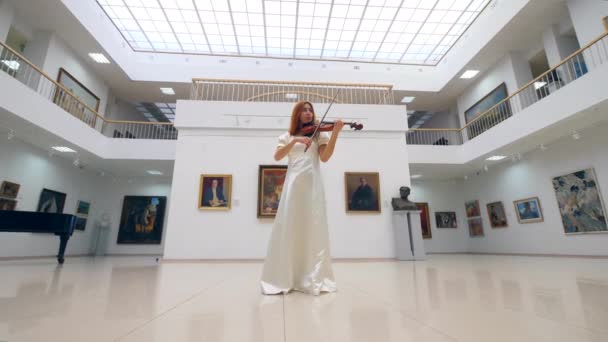 Lady in een witte jurk is het spelen van de viool in de galerij Hal — Stockvideo