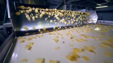 Ağır çekim bir gıda fabrikasında endüstriyel satırından düşen patates cips. 