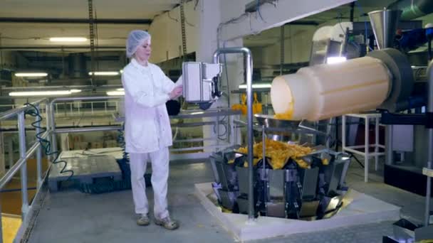 女性は、ポテトチップスを移動工場コンベヤの作業をチェックします。. — ストック動画