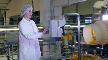 Kadın işçi bir gıda tesiste bir konveyör cips ile kontrol standları.