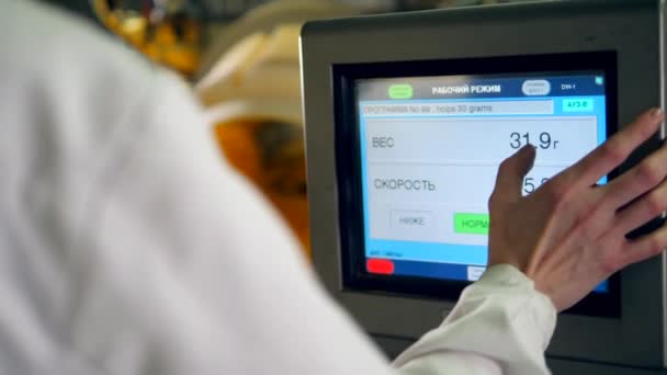 A person uses a machine to control work of a conveyor with potato crisps at a factory. — Stock Video