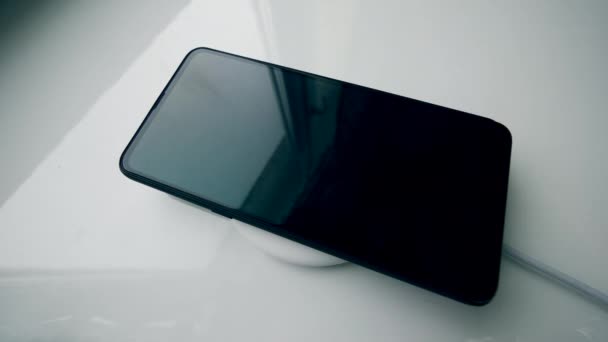 Geautomatiseerde inductie lader charginga smartphone op een tafel. — Stockvideo