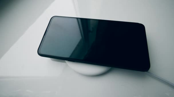 Carga de smartphone moderno en una almohadilla de un cargador inalámbrico . — Vídeo de stock
