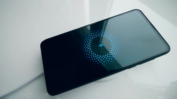 Un téléphone se recharge sur une station sans fil, montrant le niveau de la batterie .