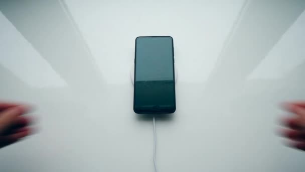 Rechargeur à induction automatisé fonctionnant avec un smartphone noir .