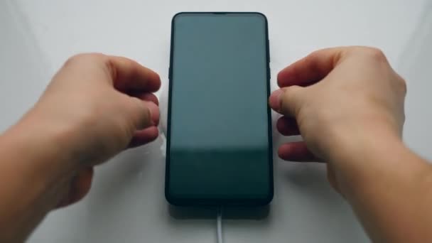 Mannelijke gebruiker plaatst een telefoon op inductie laadstation. Draadloos opladen concept. — Stockvideo