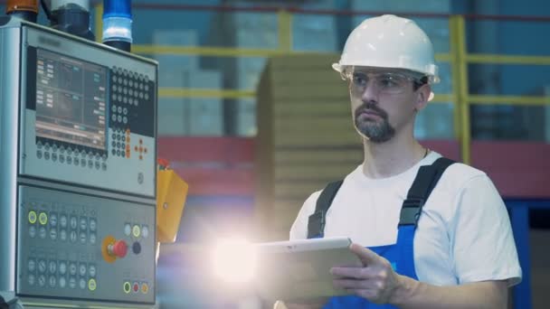 Kontrol paneli ve yanında bir tablet ile duran bir erkek teknisyen — Stok video