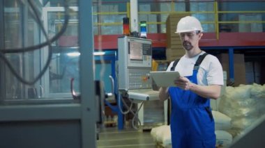 Bir tablet ile erkek mühendis endüstriyel üretim sürecini inceliyor