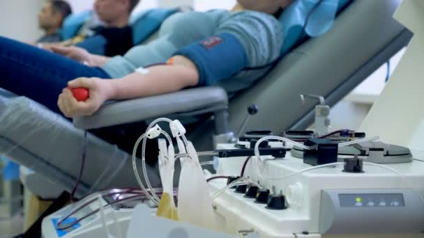 Woman squeezes a ball, donating blood in a transfusion center. — Stock Video