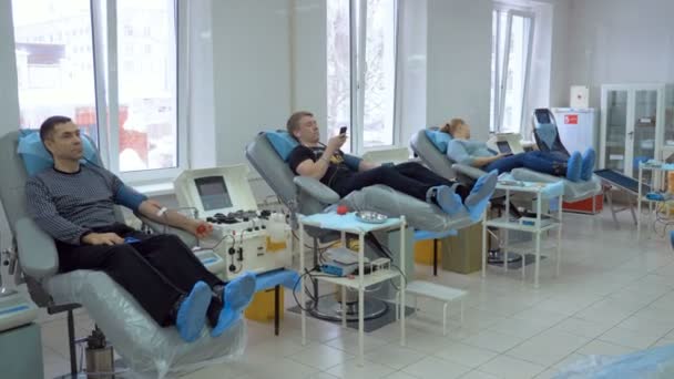 Three patients donate blood in a modern clinic, using medical equipment. — Stock Video