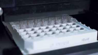 Labaratuar donanımları çalışsa da sıvı ile dolu bir tepsi üzerinde plastik tüpler.