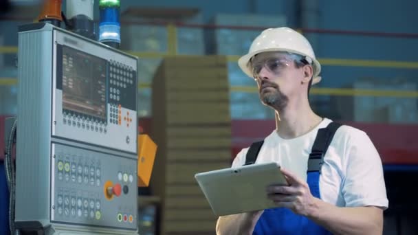 Ingeniero masculino con una tableta está de pie cerca de la placa de control — Vídeos de Stock