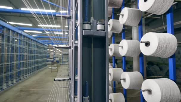 Muchas clews giran en un estante de fábrica, enrollándose con hilos. Línea de producción de textiles industriales — Vídeos de Stock