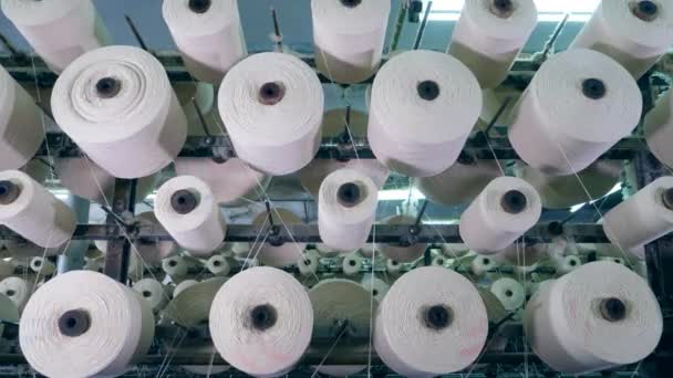 Spulen mit Fäden rotieren auf einem Gestell in einer Textilfabrik. Produktionslinie für industrielle Gewebe. — Stockvideo