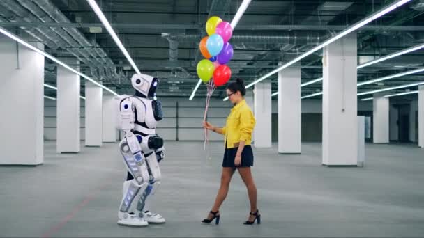 Bir kız bir odada bir robota balon hediyeleme. — Stok video