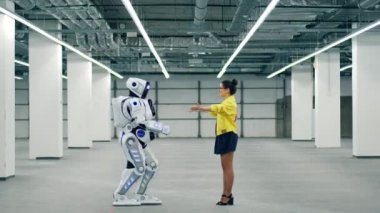 Kadın onu kucaklıyor, robot arkadaşı selamlıyor.