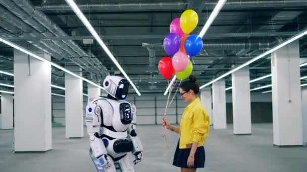 年轻女子给了她的朋友机器人许多五颜六色的气球. — 图库视频影像
