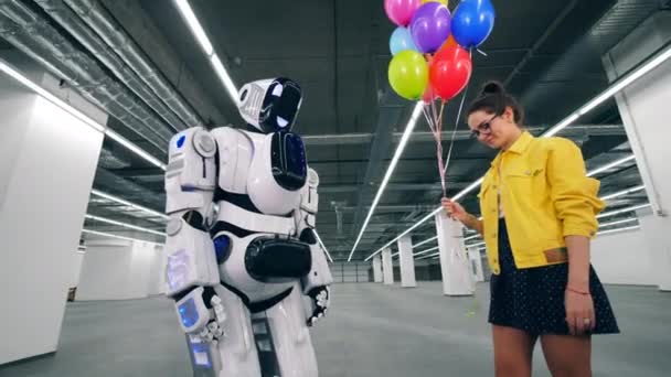 Fille cadeaux un tas de ballons à son ami droïde dans une chambre . — Video