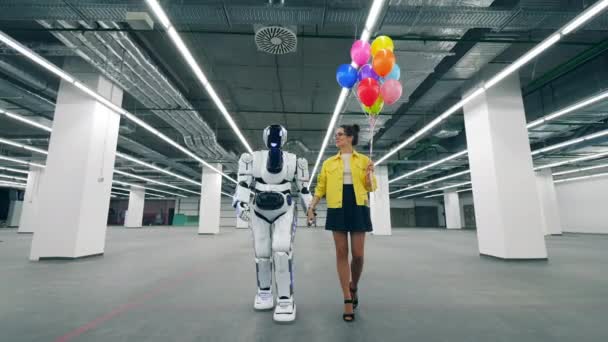 Una mujer sostiene globos en la mano mientras camina en una habitación con cyborg . — Vídeos de Stock