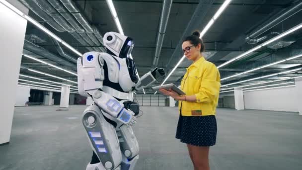 En flicka arbetar med en tablett, kontrol lera en vit Droid. — Stockvideo