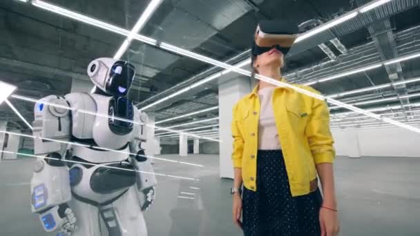 One girl uses VR glasses in a room and touches droids hand. — Stock Video