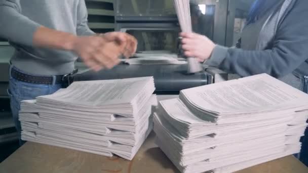 Les gens retirent des piles de papier d'un convoyeur typographique . — Video