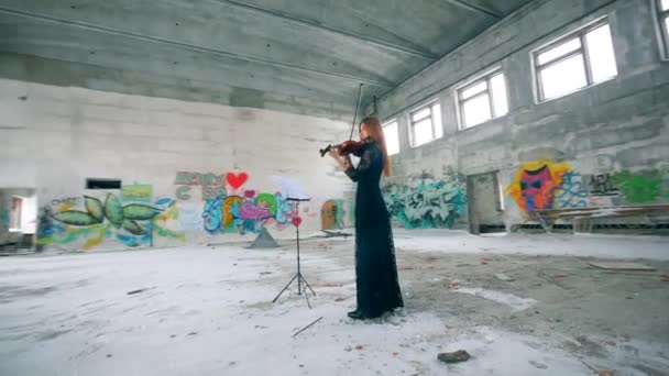 Заброшенное здание с граффити и женщиной, играющей на скрипке — стоковое видео