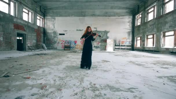 바이올린을 연주하는 동안 빨간 머리 여자는 복도를 따라 걷고 있다 — 비디오