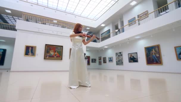 ギャラリーでバイオリンを演奏中の白いドレスの女性 — ストック動画