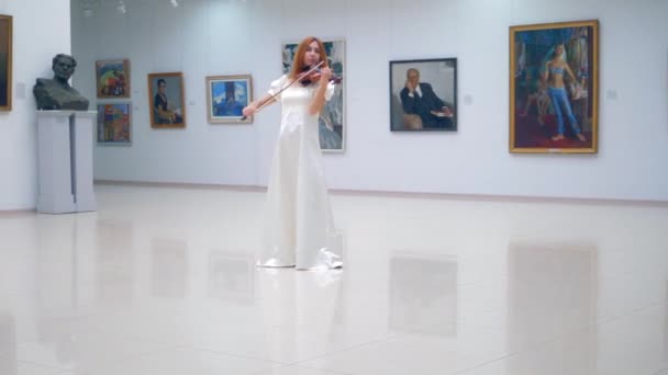 Belle femme dans une robe blanche joue du violon dans la galerie — Video