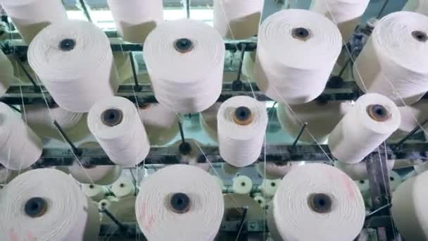 White fiber rolling on bobbins, placed on a factory rack. — Stock Video