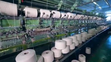Büyük bobinler döner, dikiş ipliklerini fabrika makinelerinde biriktirme.