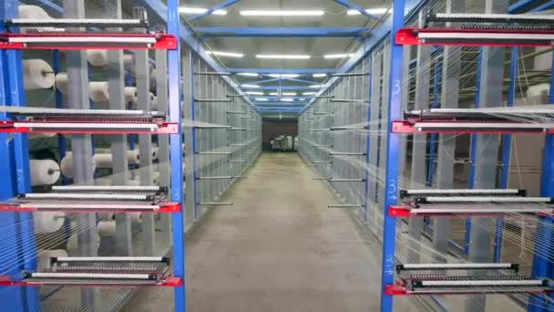 Fiber bobbins rotate on racks in a big facility. — Stock Video