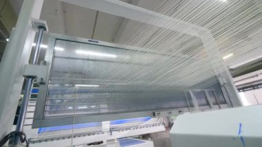 Modern dokuma makinesi beyaz kumaş dizeleri ile çalışır.