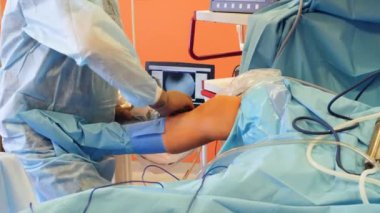 Cerrah bir bacak üzerinde mekanik aletler ile bir operasyon tutuyor